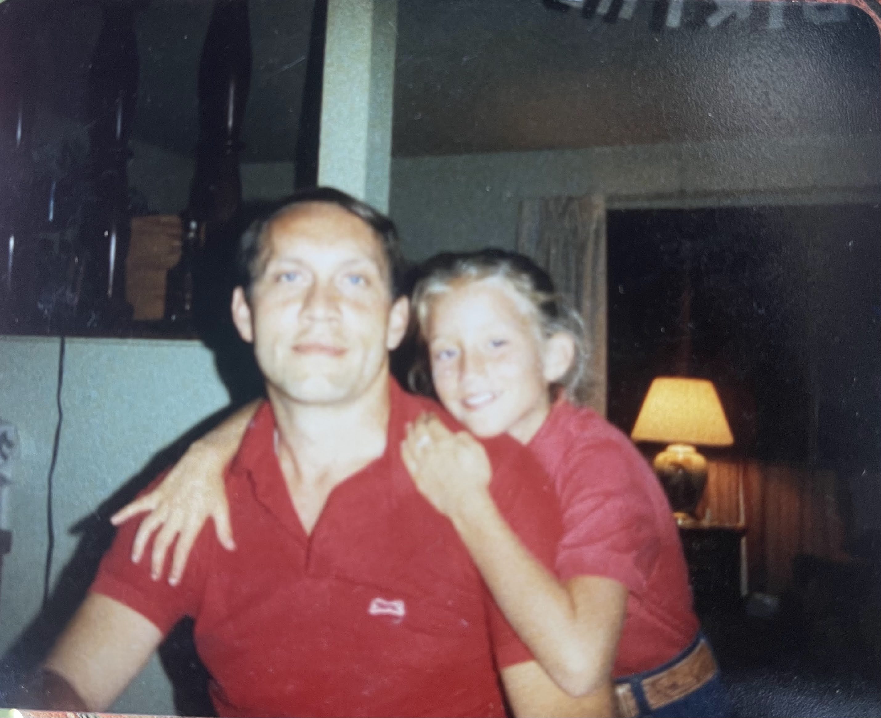 Young Charmagne hugging her dad, both wearing red shirts